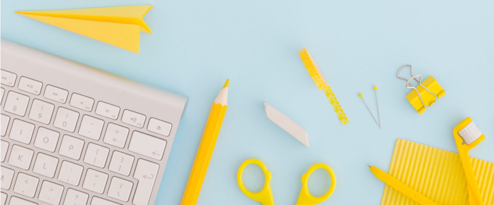 Image of a keyboard with yellow scissors and desk items