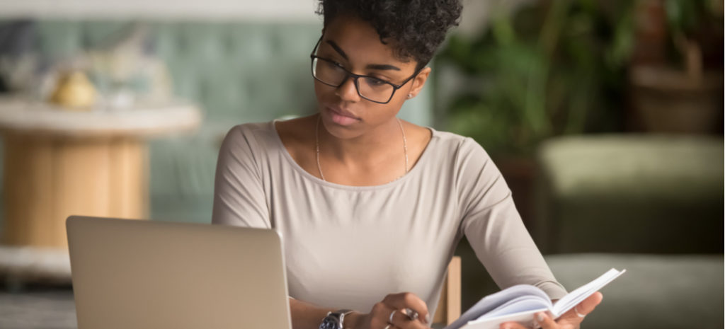 Photo of woman looking at laptop and taking notes about WordPress