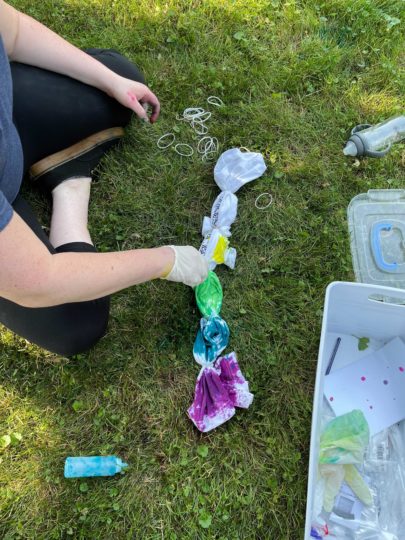 An employee tie dyes a shirt during Pride week