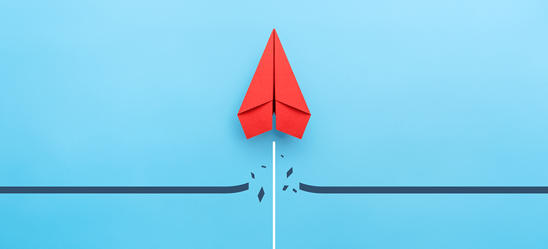 a red paper airplane breaks through a solid black line on a blue background