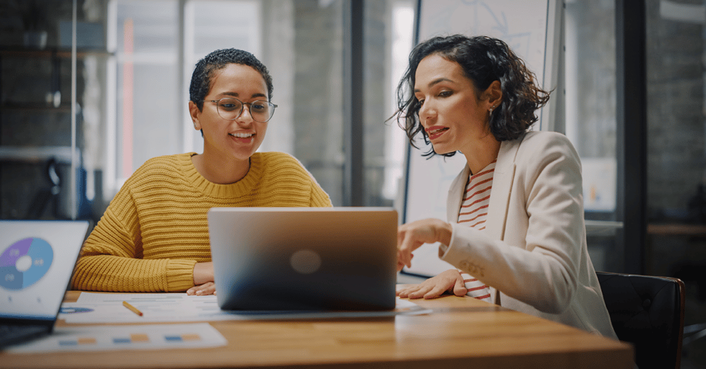 two women work over a shared screen