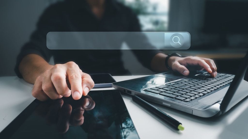 a man browses online stores on a laptop. An overlay of an empty search bar is at the forefront of the image