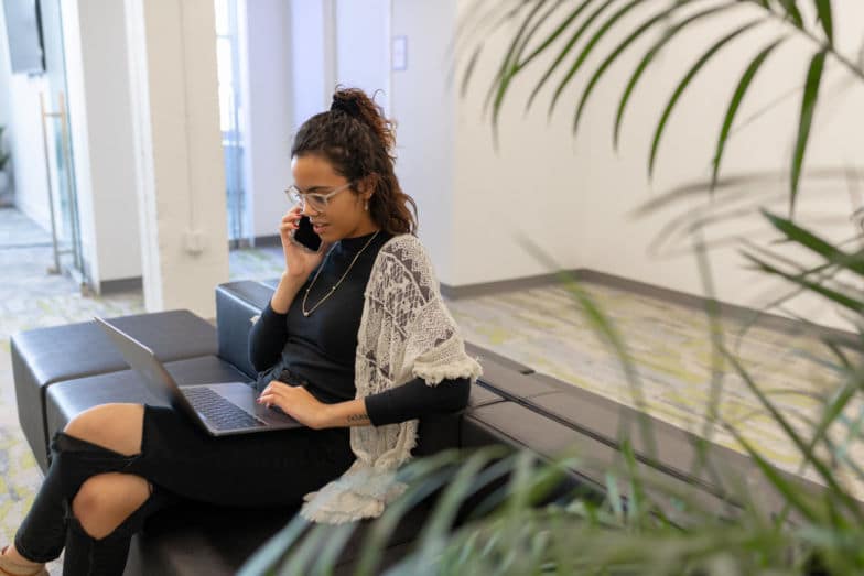 a woman chats on the phone about a project while working on a laptop