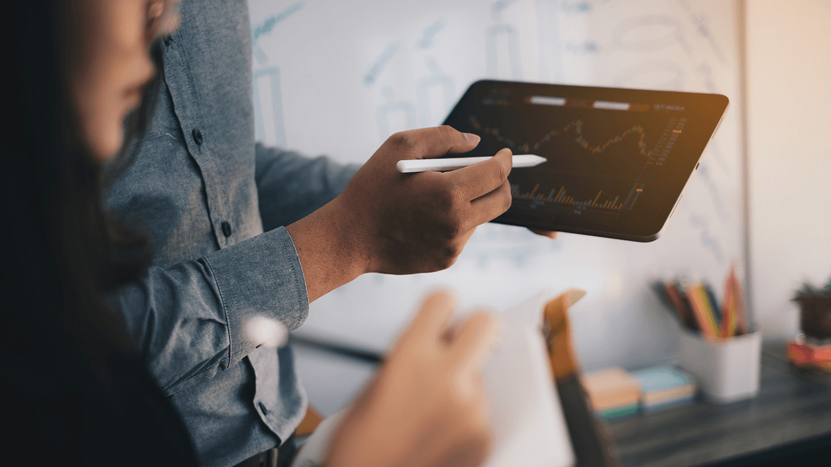 Two agency employees look at a colorful graph on a tablet.