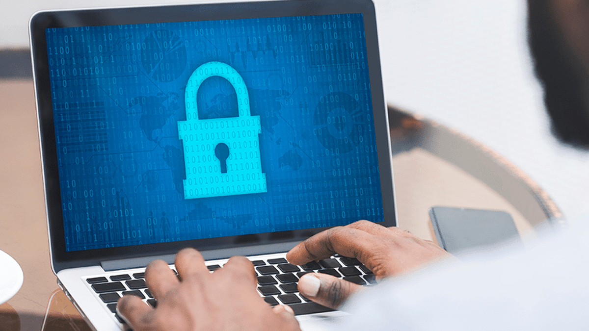 a person working on cybersecurity using a laptop which displays a large padlock icon